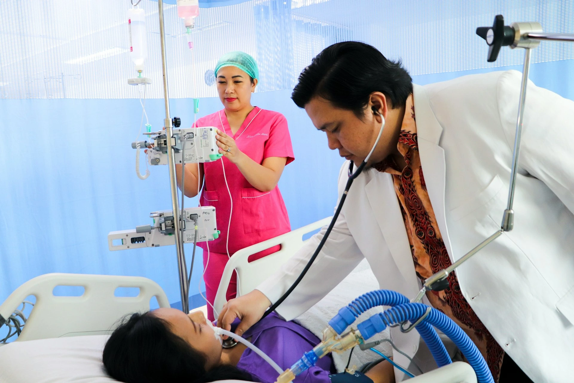 a man laying in a hospital bed being examined by a nurse